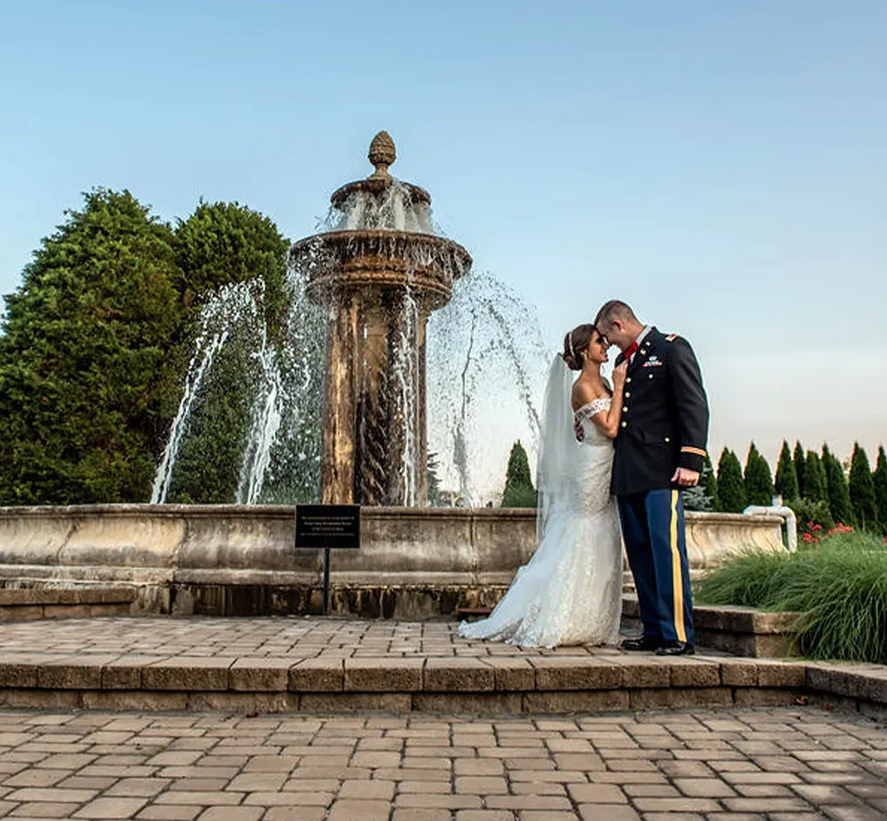 Bride and groom embracing next to outdoor fountain