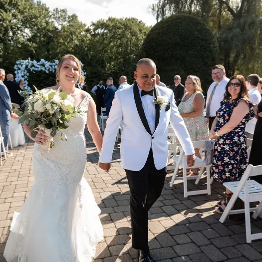 Bride and groom walk outside as guest look on